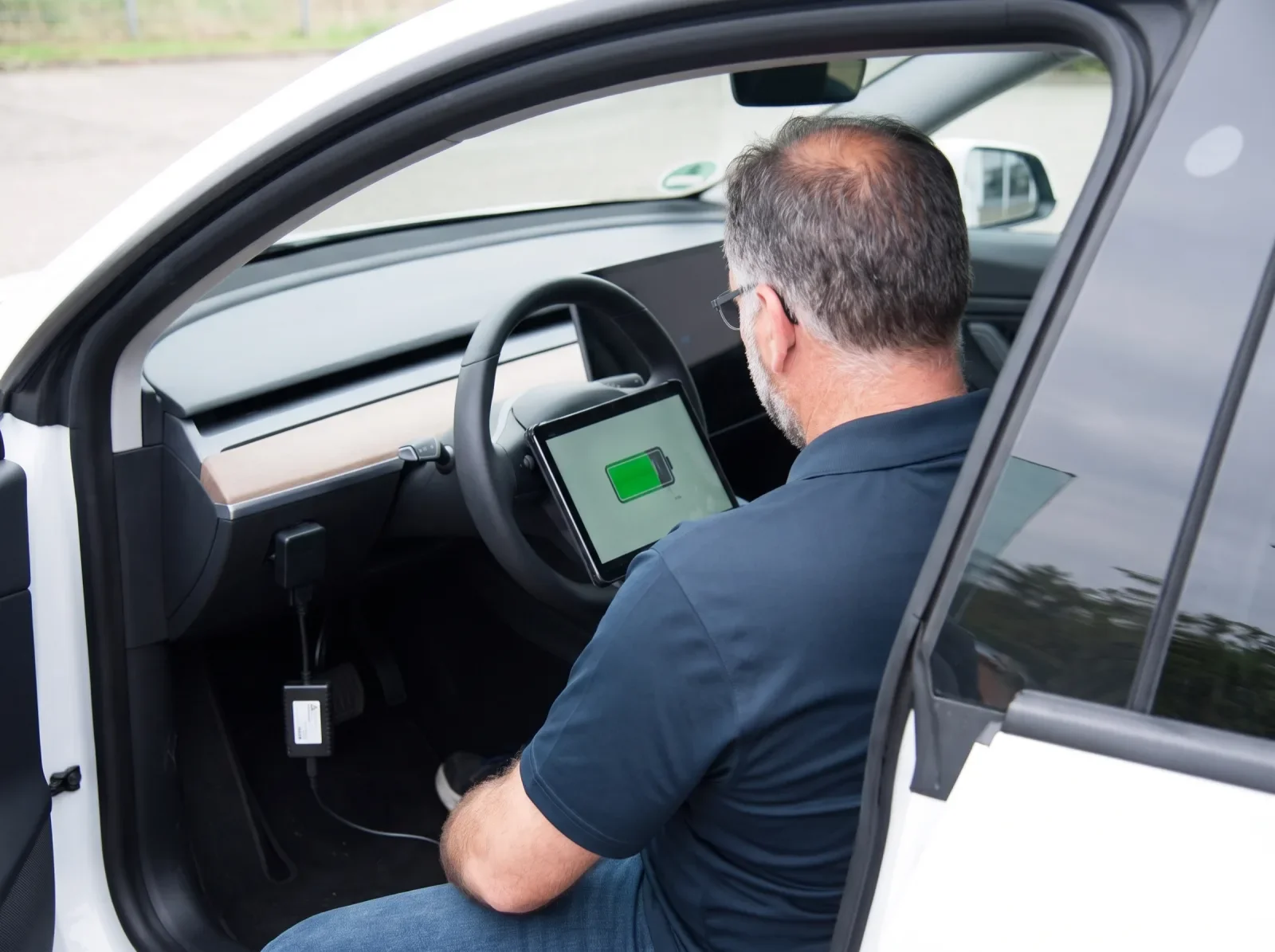 Batterietest im Innenraum eines Elektroautos, das Tablet zeigt den Ladezustand